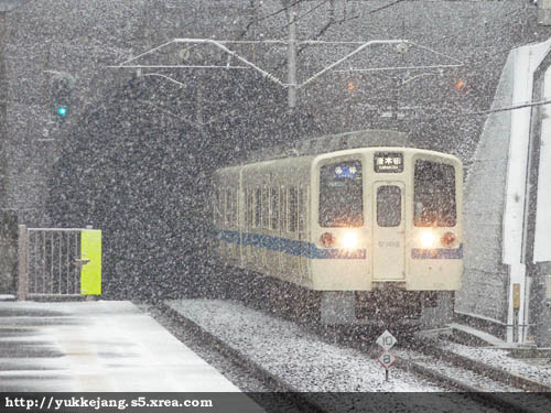 雪が舞う中、駅に進入する小田急9000系
